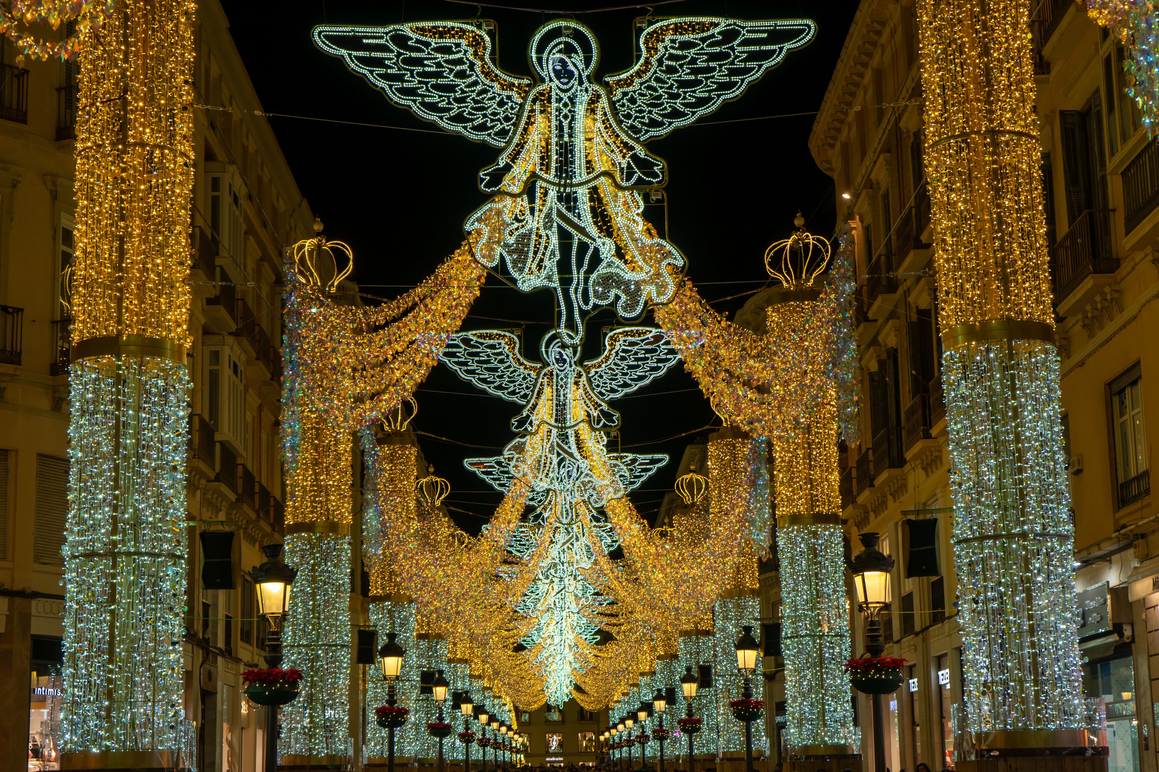 A decorated street with a large illuminated angel structure and festive lights.