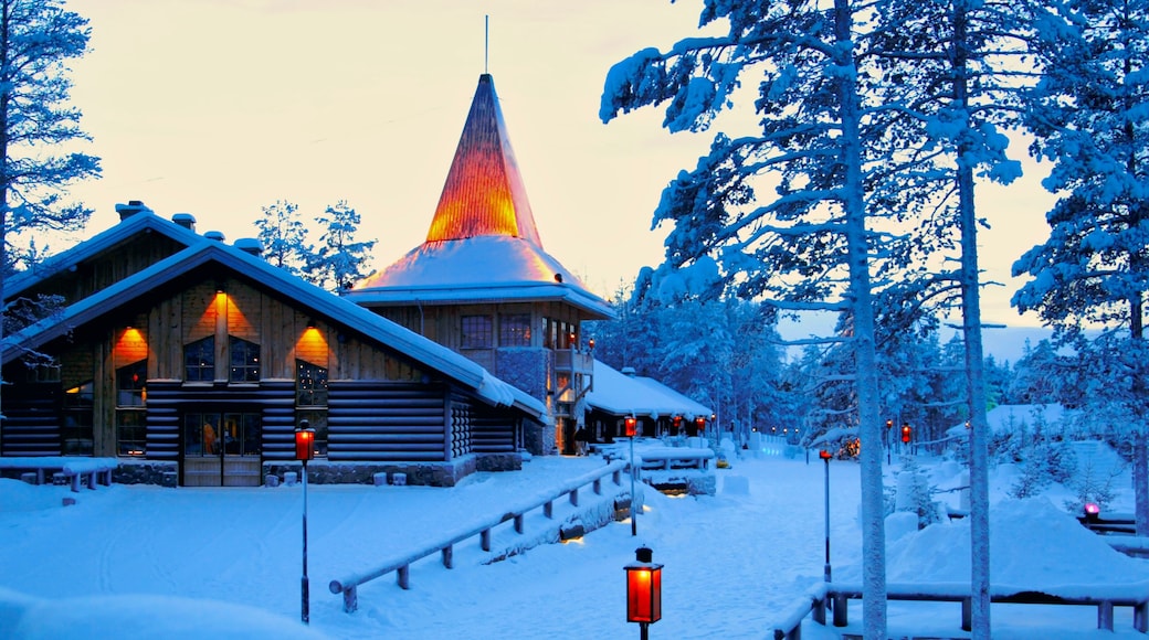 A snow-covered lodge with a conical roof and a wooden facade, surrounded by snow-laden trees.