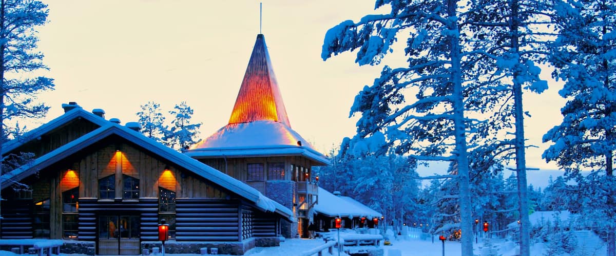 A snow-covered lodge with a conical roof and a wooden facade, surrounded by snow-laden trees.