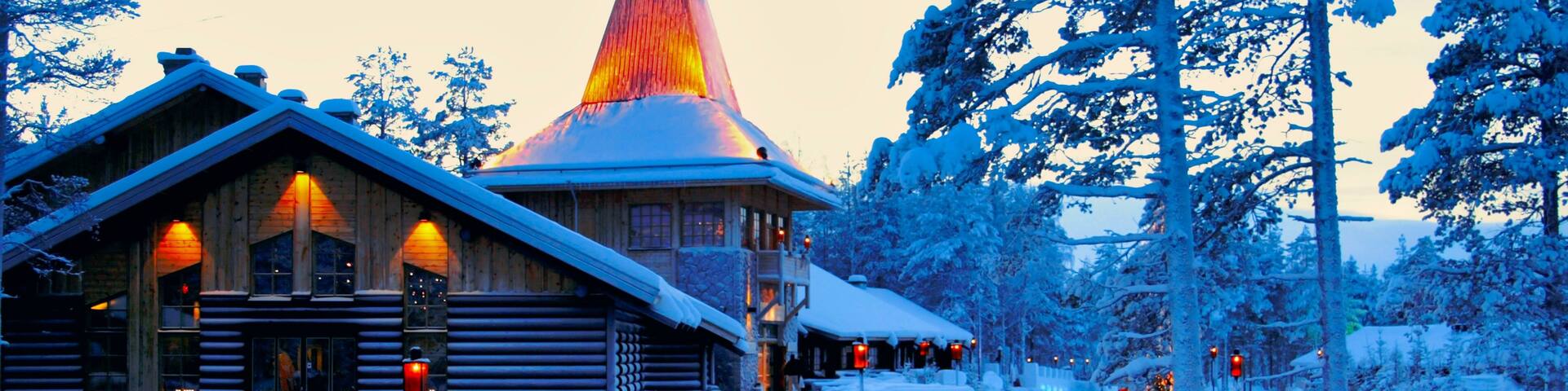 A snow-covered lodge with a conical roof and a wooden facade, surrounded by snow-laden trees.
