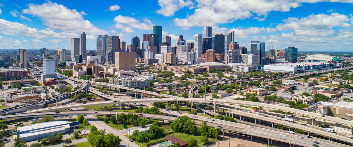 A city skyline with modern skyscrapers, a highway system, and a stadium.