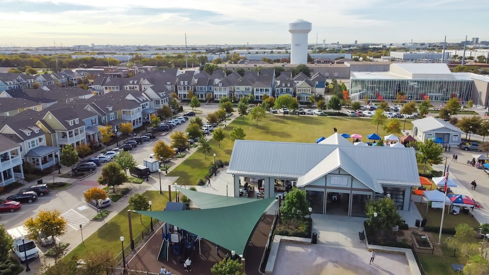 A residential area with houses, a playground, a large water tower, and a modern building.