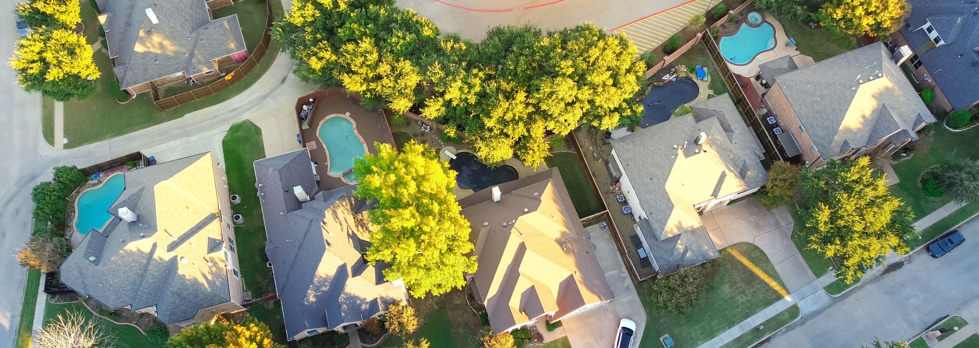 A residential area with houses, a swimming pool, and a road.
