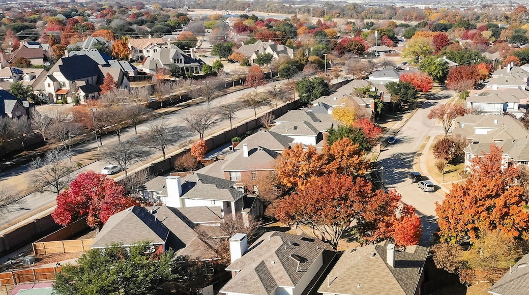 Panorama top view beautiful neighborhood in Coppell, Texas, USA in autumn season. Row of single-family home with attached garage, garden, surrounded by colorful fall foliage leaves under blue sky