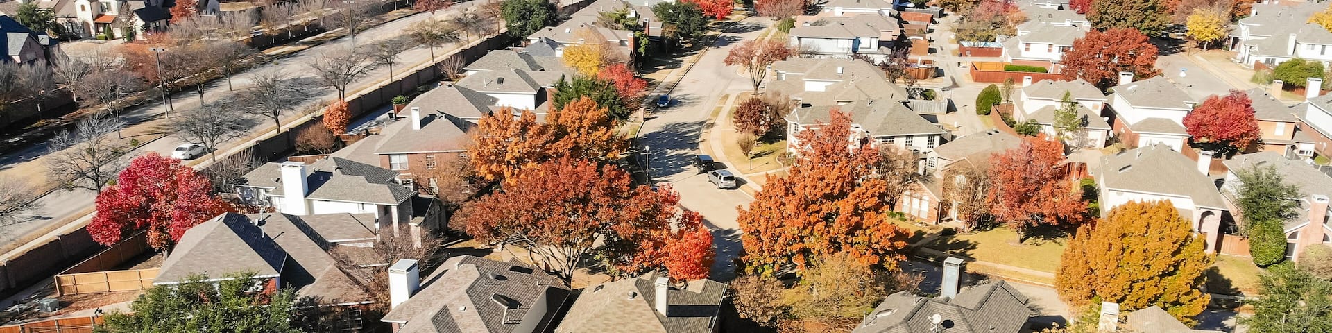 Panorama top view beautiful neighborhood in Coppell, Texas, USA in autumn season. Row of single-family home with attached garage, garden, surrounded by colorful fall foliage leaves under blue sky