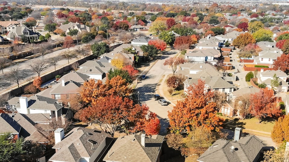 A suburban neighborhood with houses and autumn-colored trees.