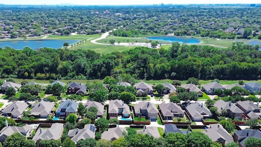 A residential area with houses, a golf course, and two lakes.