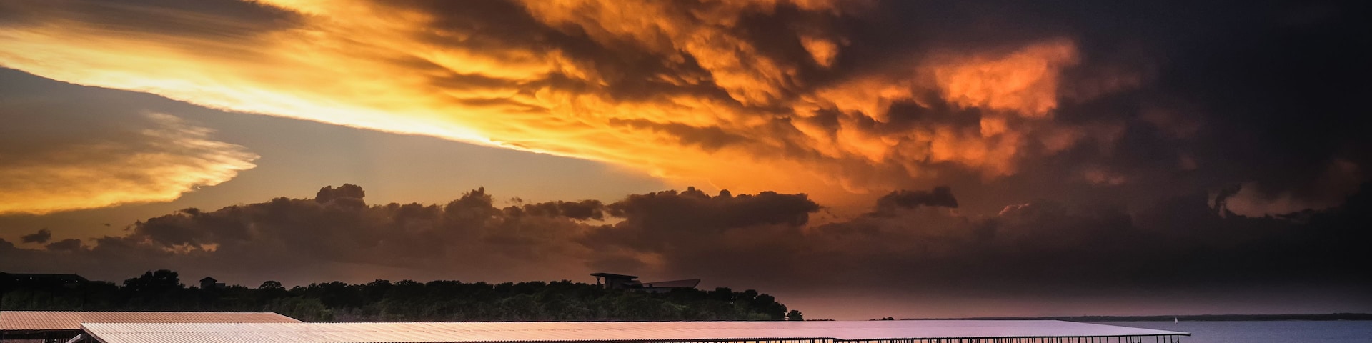 Un muelle con barcos amarrados, un cielo al atardecer y una masa de agua tranquila.