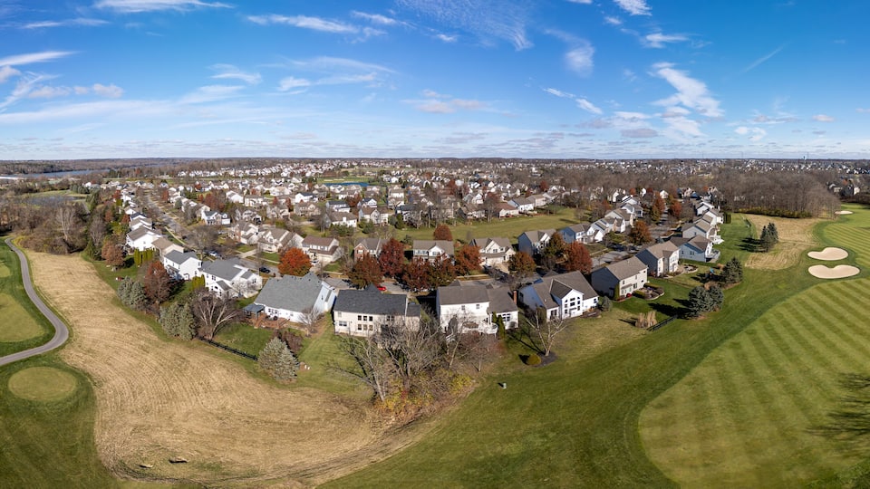 A residential area with houses, a golf course, and a river in the background.