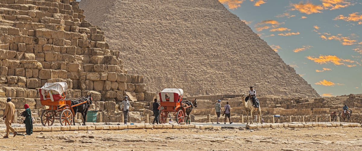 Bedouin men and tourists, in front of the Giza Necropolis pyramids complex. Egypt