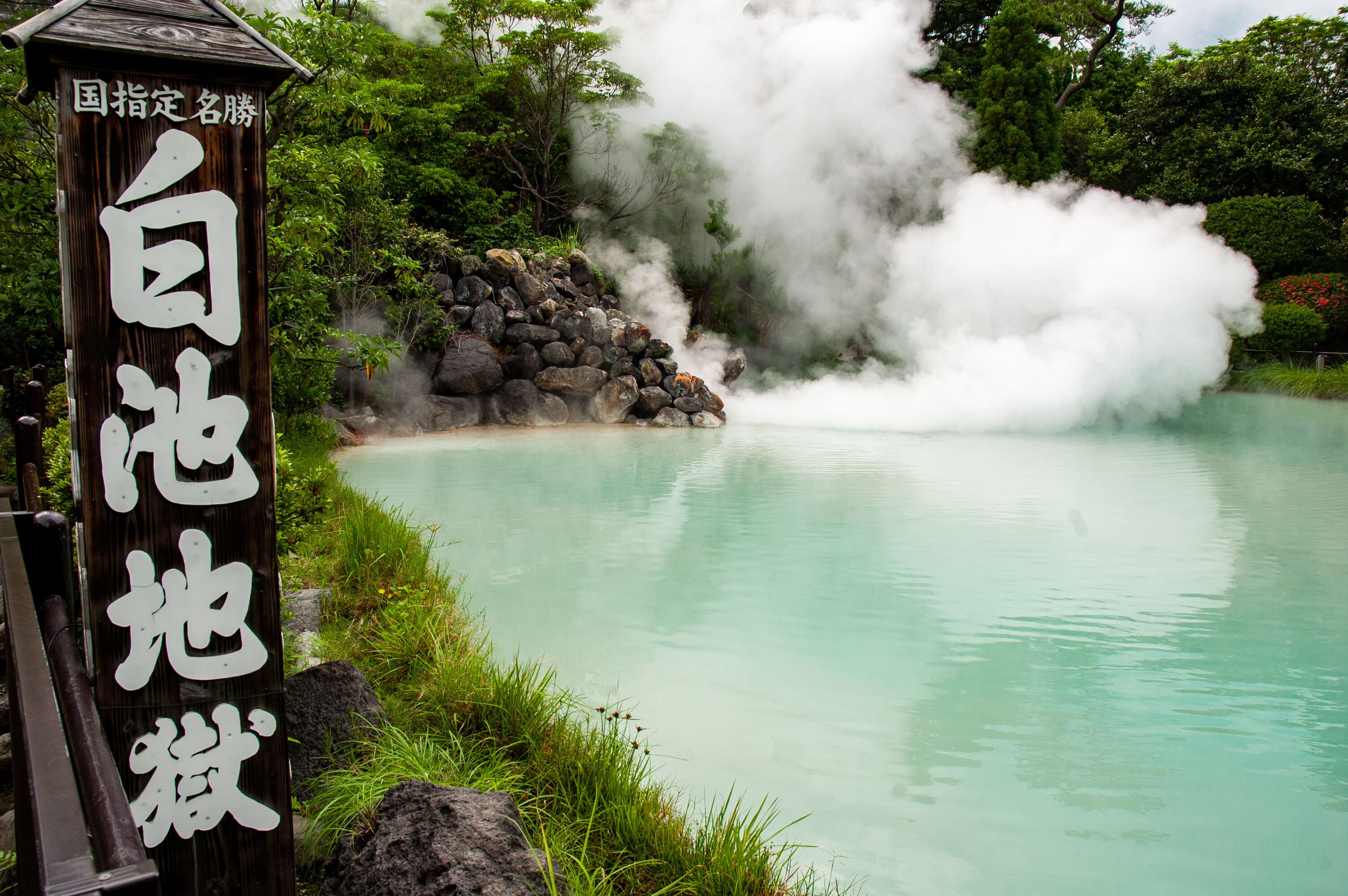 A nameplate writes "Shiraike Jikoku" (means White Pond Hell) in Japanese, one of the eight hells in Beppu, Oita, Japan. It is a hot spring in pale blue color which the color is caused by the mist