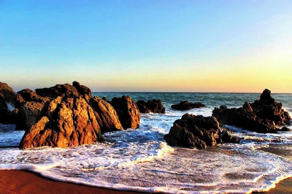 Una costa rocosa con olas rompiendo contra la orilla.