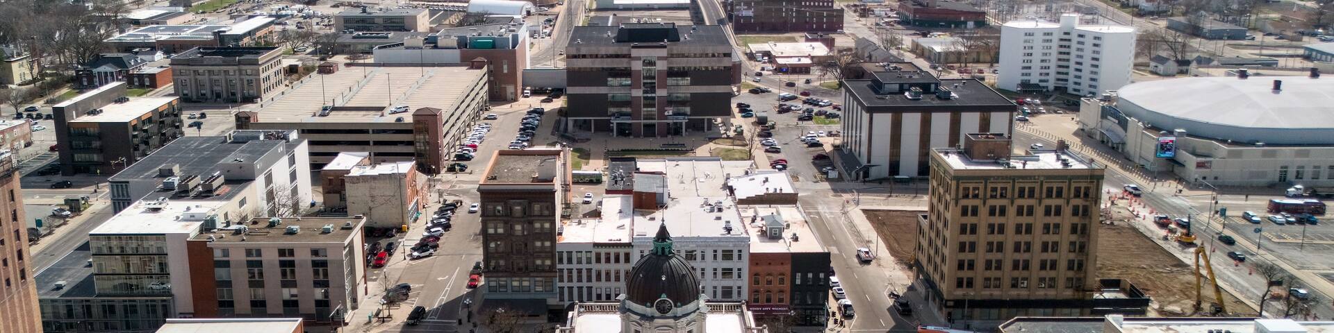 A cityscape with a prominent historic building with a dome, surrounded by modern buildings and busy streets.