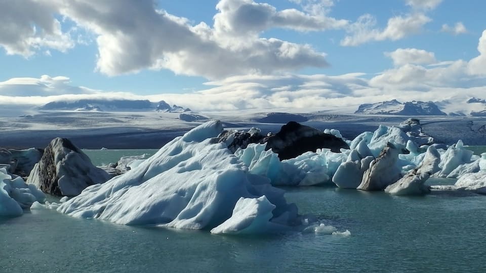 Icebergs in a body of water with mountains in the background.