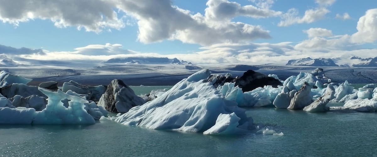 Icebergs in a body of water with mountains in the background.