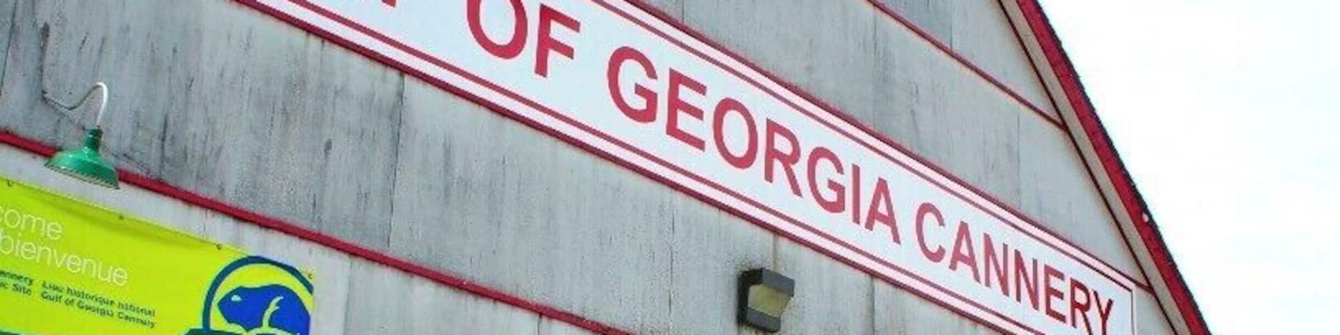 A large building labeled 'Gulf of Georgia Cannery' with a wooden dock and a person standing nearby.