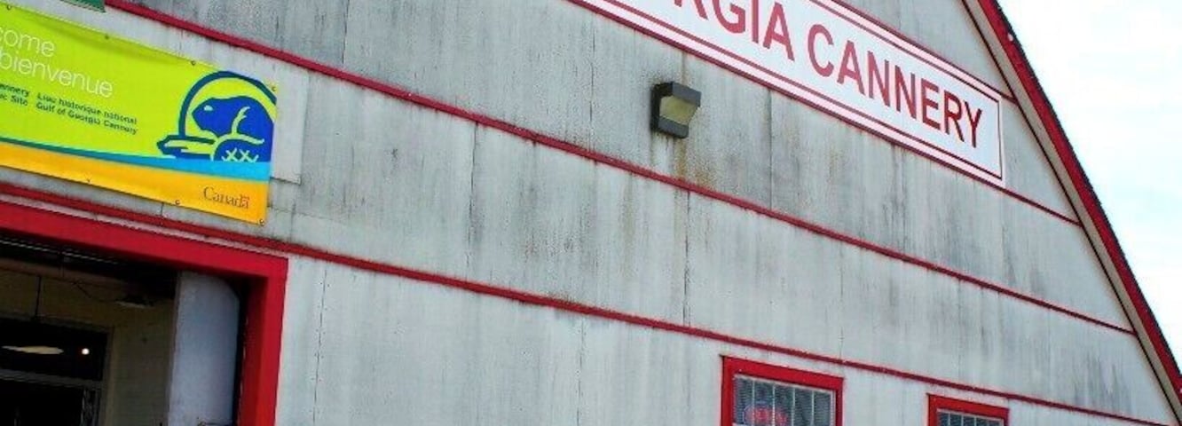 A large building labeled 'Gulf of Georgia Cannery' with a wooden dock and a person standing nearby.