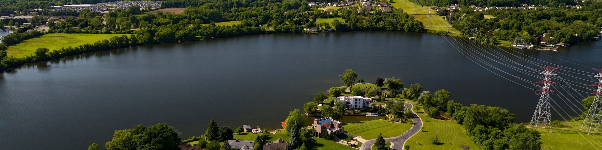 Un lago rodeado de vegetación, un campo de golf y líneas eléctricas.