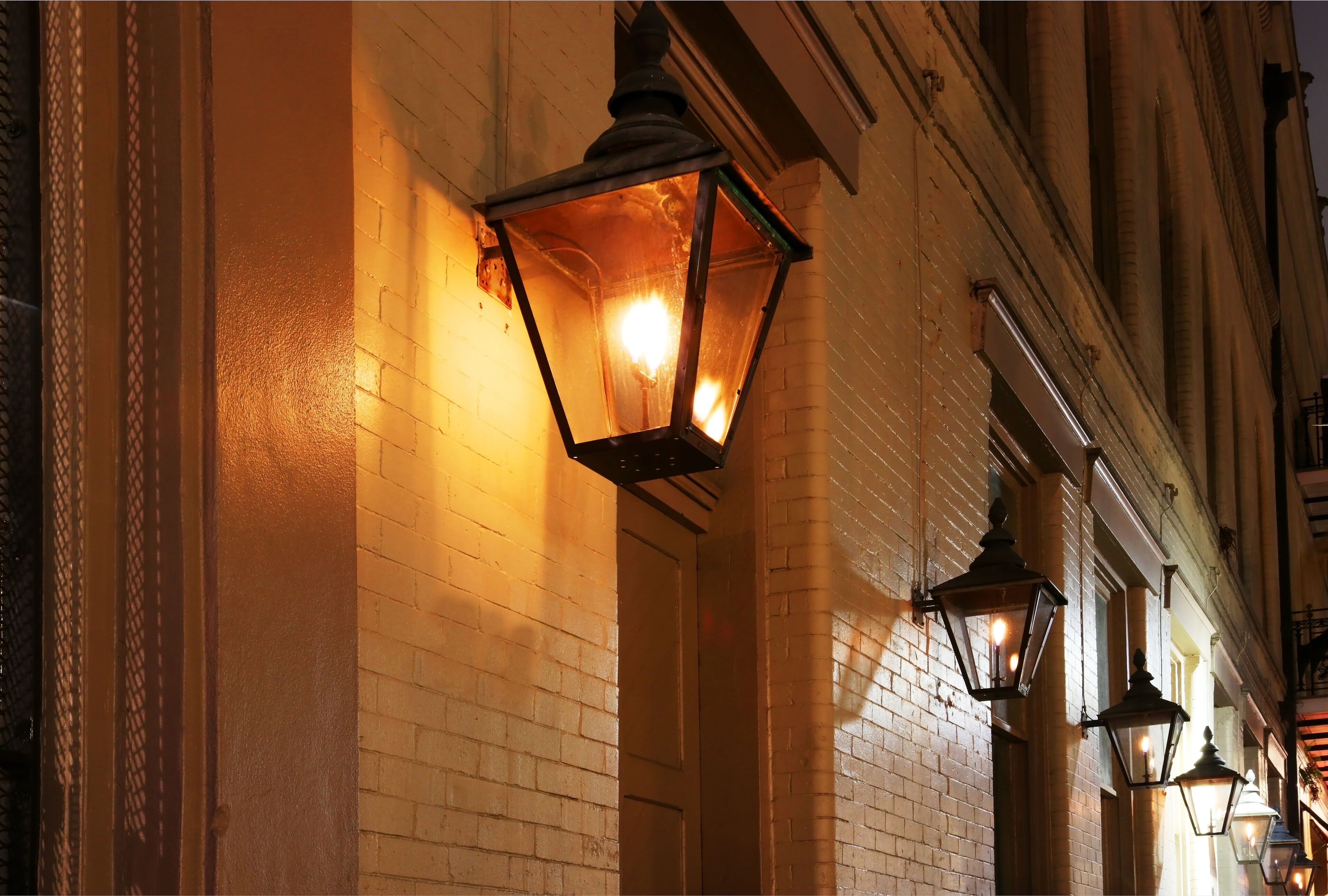 New Orleans French Quarter gas lights. Night street view with glowing real gas lanterns on the outdoor wall one of the building in the famous French Quarters, New Orleans, Louisiana, USA.