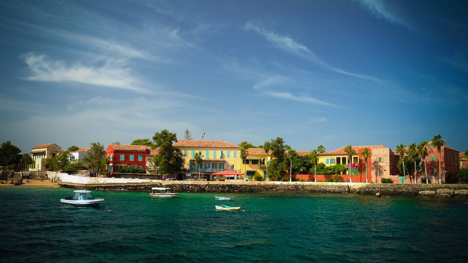 A coastal town with colorful buildings, a clear blue sky, and boats on the water.