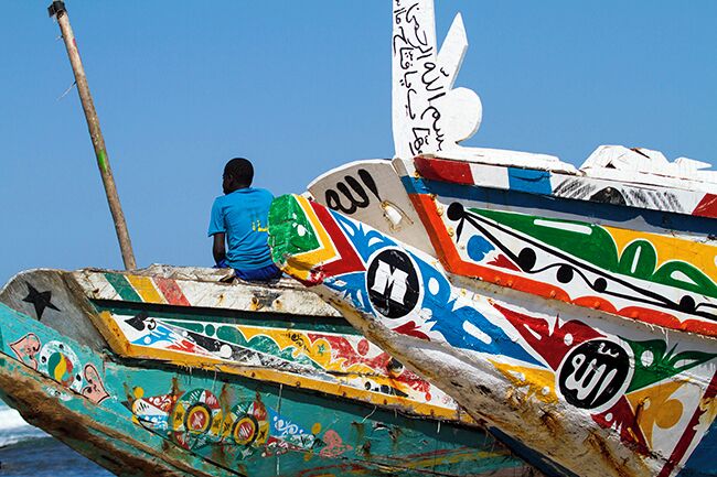 A colorful boat with graffiti, a person in a blue shirt, and a clear blue sky.