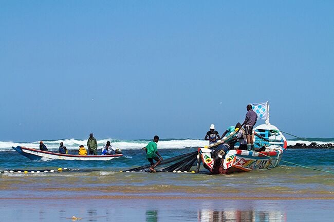 A beach with boats and people.
