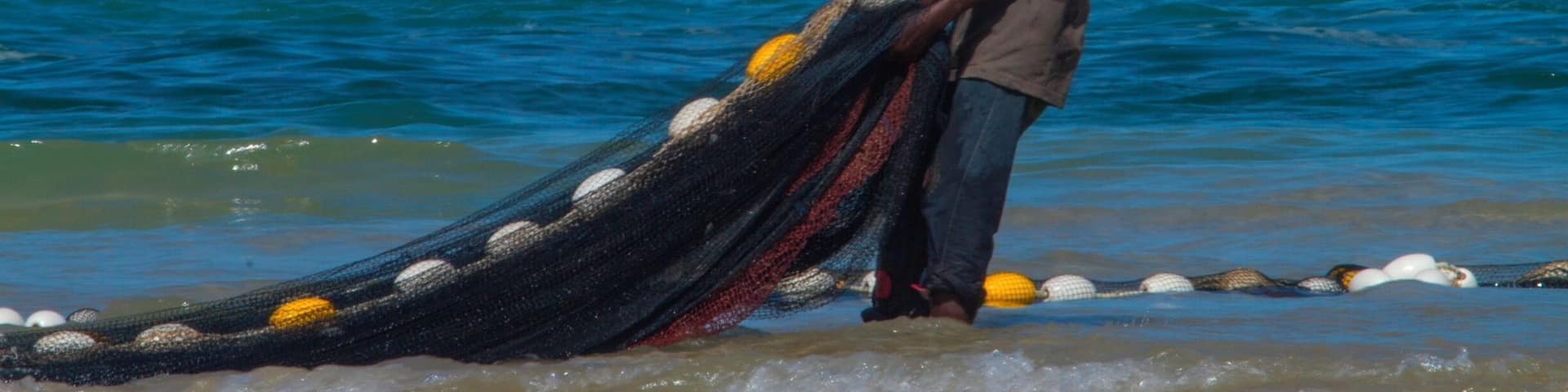Fisherman sorting out his net on the beach in Youff. Yoff is a neighborhood in Dakar, but it is also a separate town with its own peculiarities. Yoff is known for its Muslim Community Council and its fishing villages and is considered slightly more conservative than more central parts of Dakar. To get a proper impression of traditional fishing and the beautiful pirogues a visit to the district Yoff is a good idea. Yoff is the most northeastern district of Dakar and adjoins the airport in the west. Read more on blog: http://www.travelwithallsenses.com/fishermen-of-yoff/