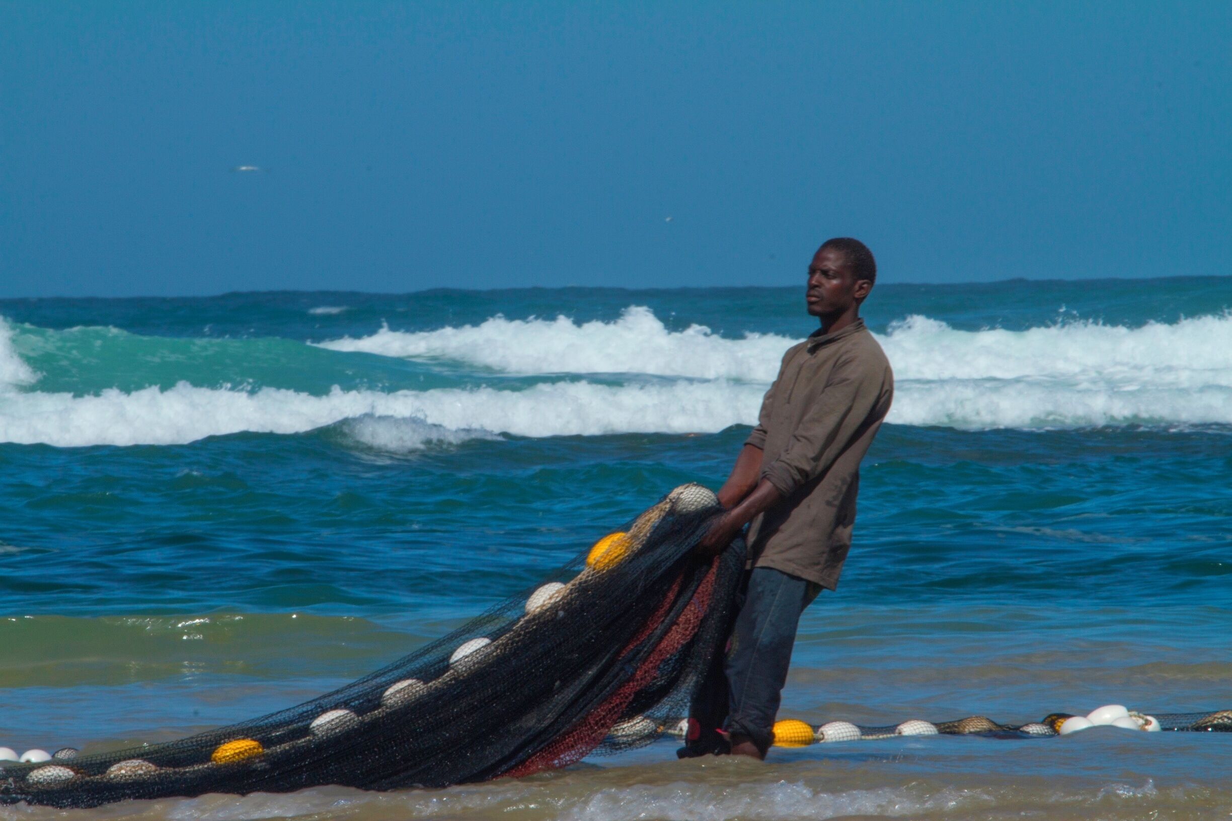 A man standing on a beach with waves crashing in the background.