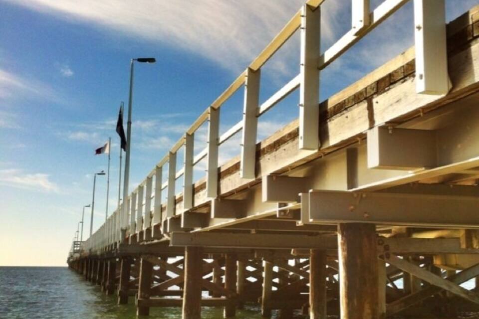 A pier extending into the water with a clear sky above.
