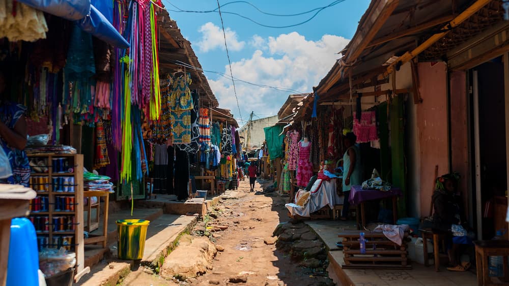 view of colorful open air street market in doula cameroun during sunny day with traditional clothes