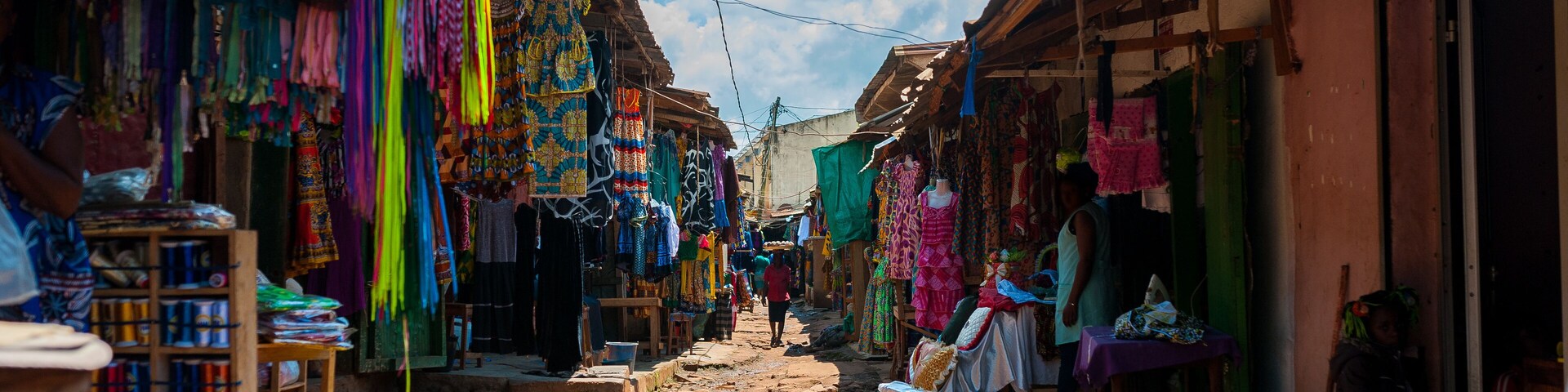A narrow street with colorful textiles and wooden buildings.