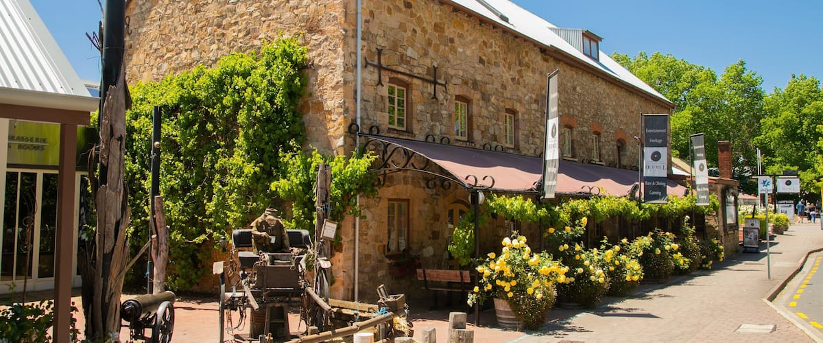 A stone building with a sign for "Brasserie Rue" and a vintage carriage parked in front.