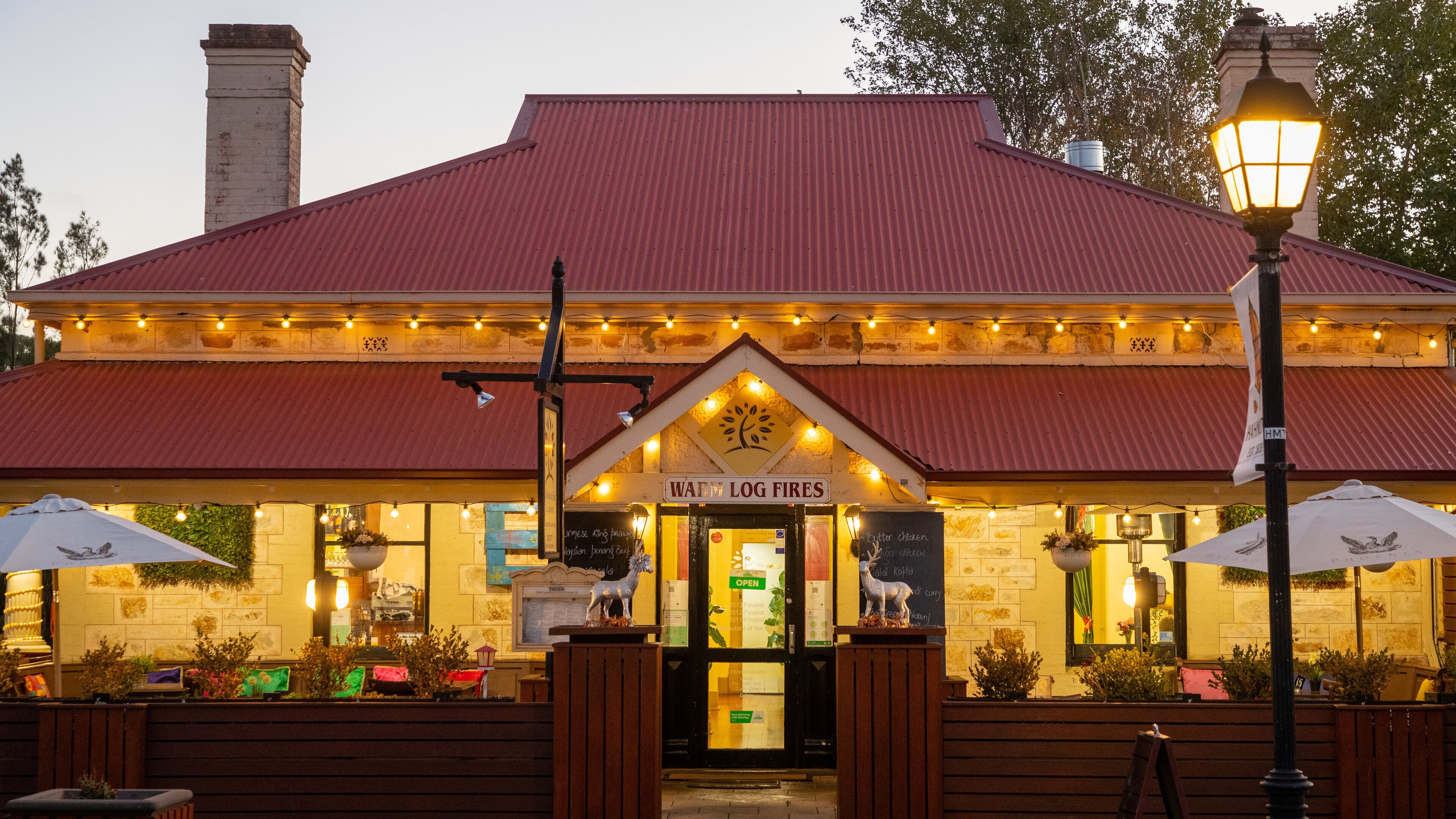 Un restaurant avec un toit rouge et une enseigne indiquant : « Cheminées à bois chaleureuses ».