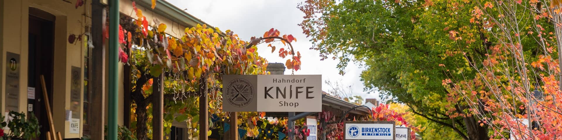 A street with shops, including a knife shop, and people walking.