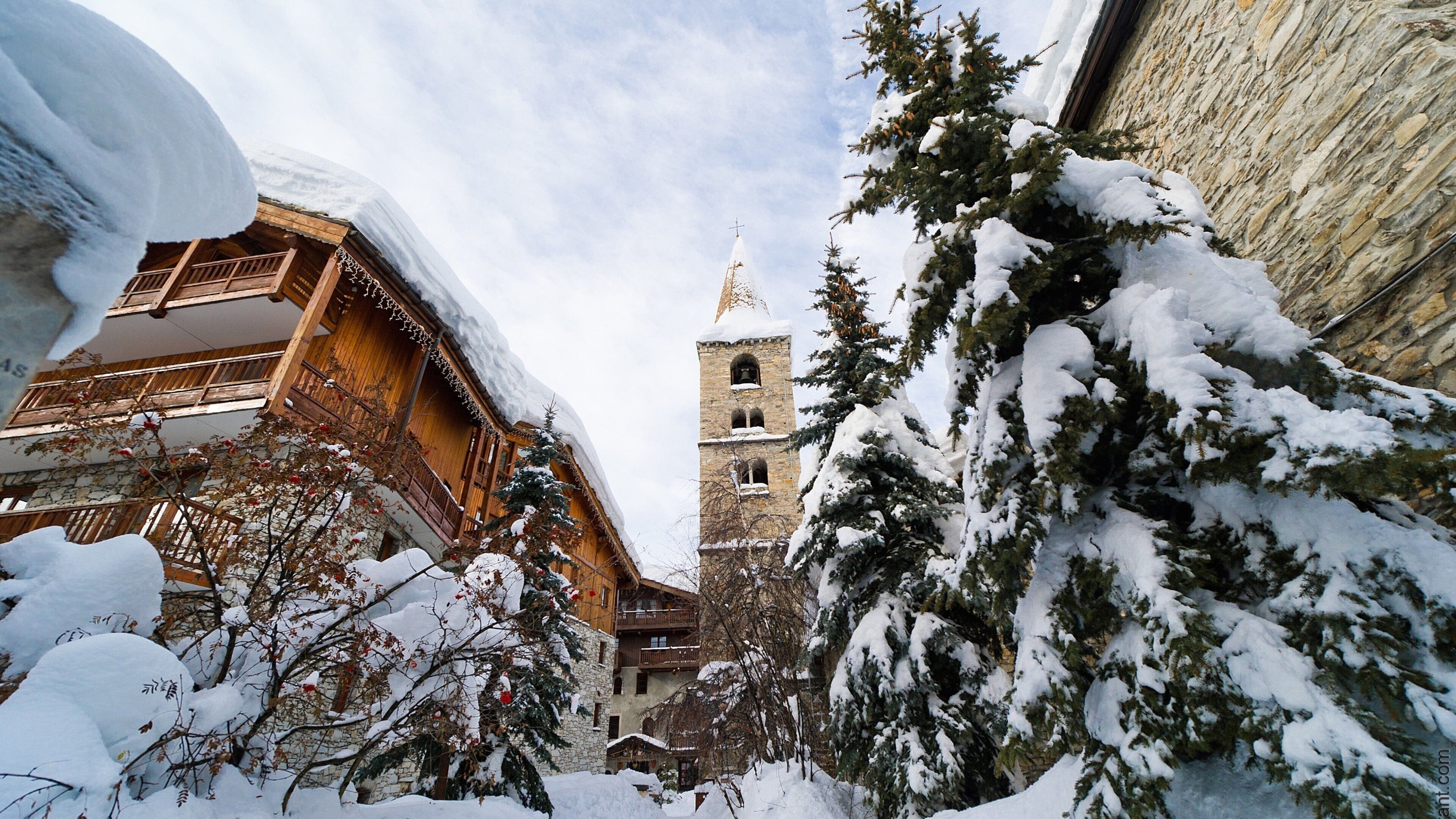 A snow-covered building with a bell tower and a stone wall.