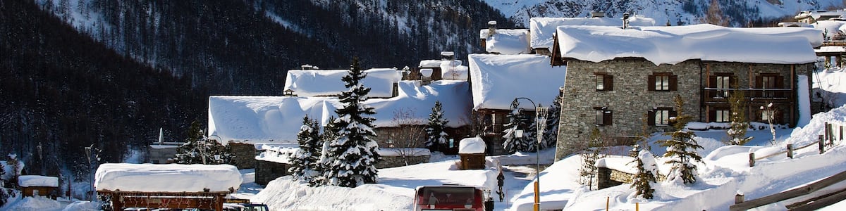 Un village de montagne enneigé, avec des bâtiments en pierre et un télésiège.