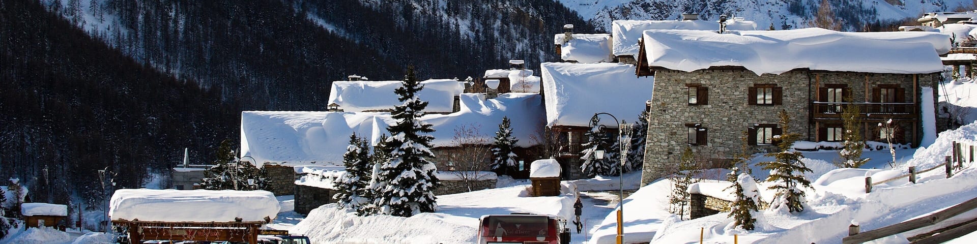 A snow-covered mountain village with stone buildings and a ski lift.