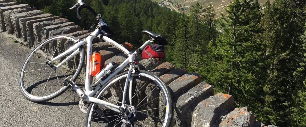 A bicycle parked on a stone wall with a mountainous landscape in the background.