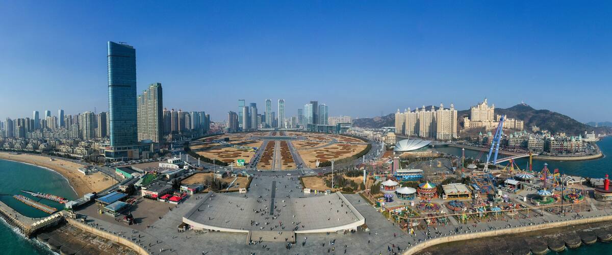 A coastal cityscape with a prominent skyscraper, a beach, and a large amusement park.