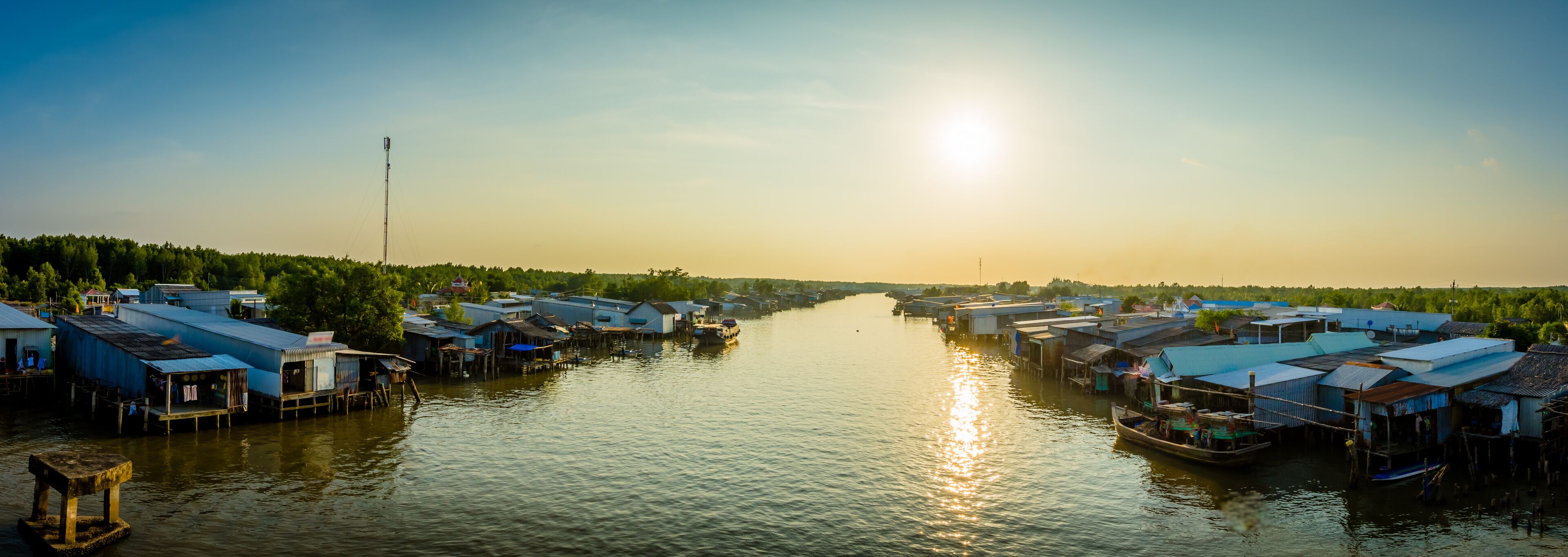 A river with floating houses and a boat.