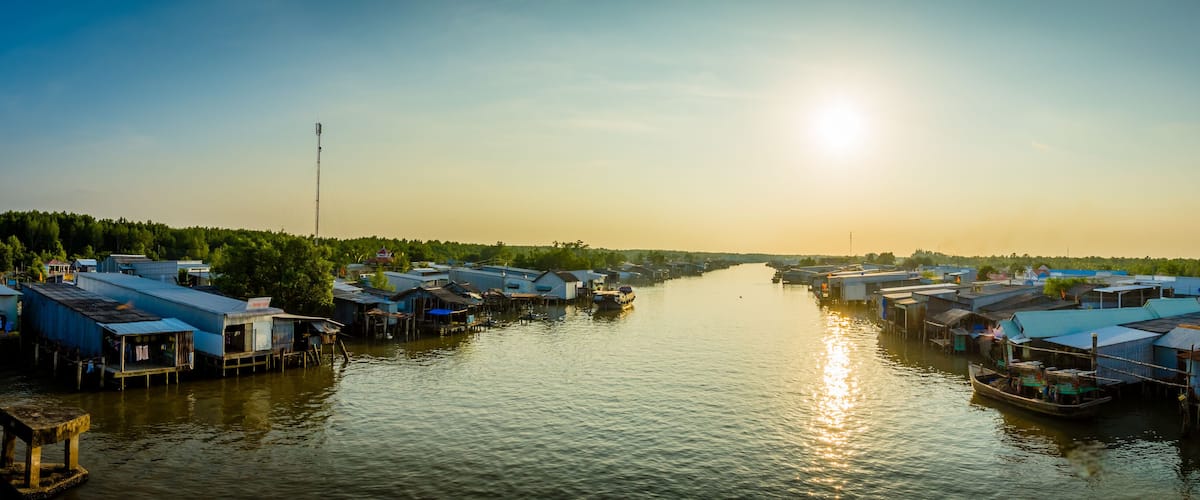 A river with floating houses and a boat.