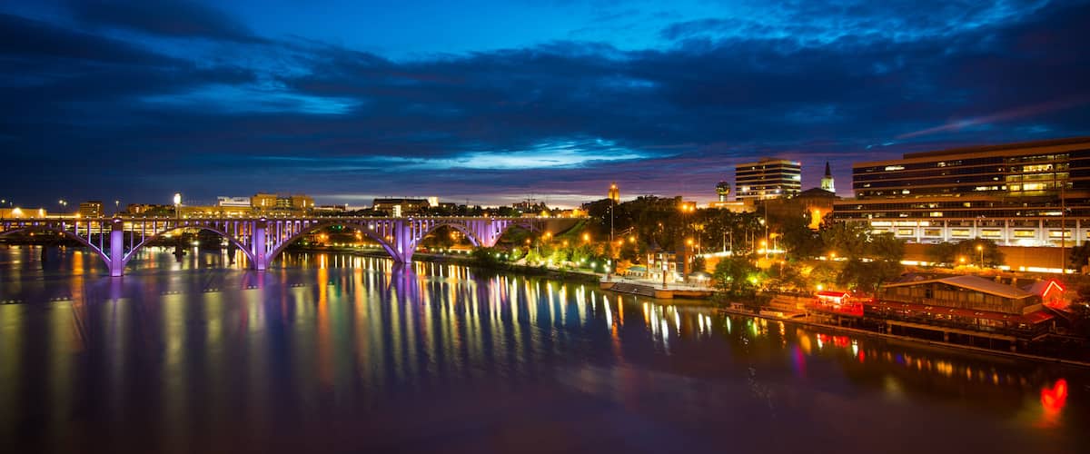 A nighttime cityscape with a bridge reflecting lights on a calm river.
