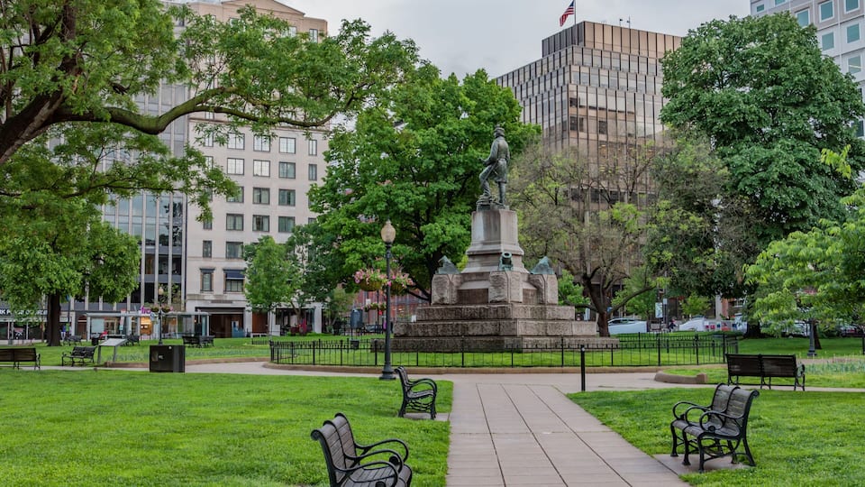 A park with a statue, benches, and a pathway.