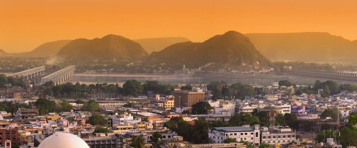 A cityscape with a prominent bridge, a river, and mountains in the background.