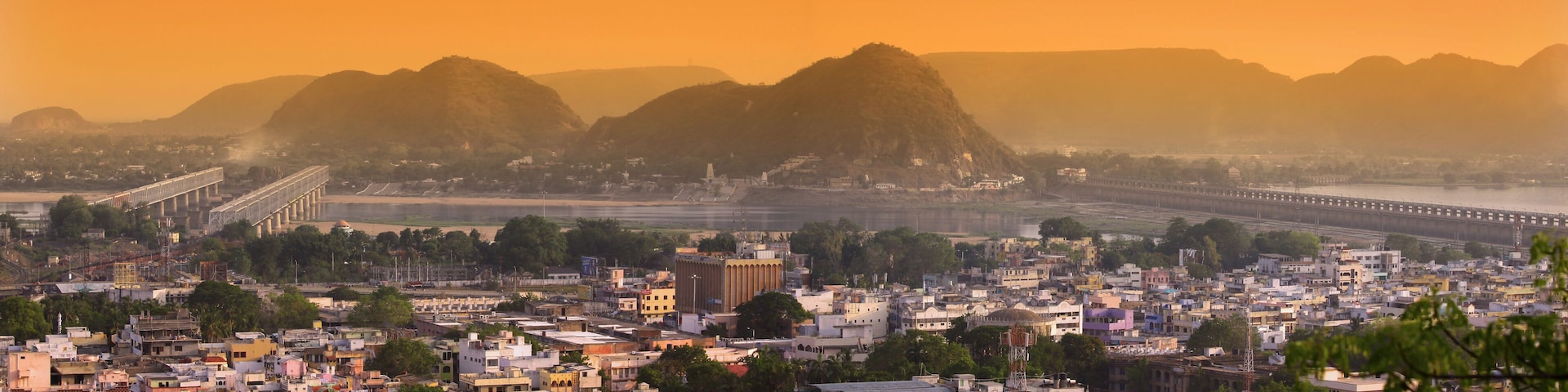 A cityscape with a prominent bridge, a river, and mountains in the background.