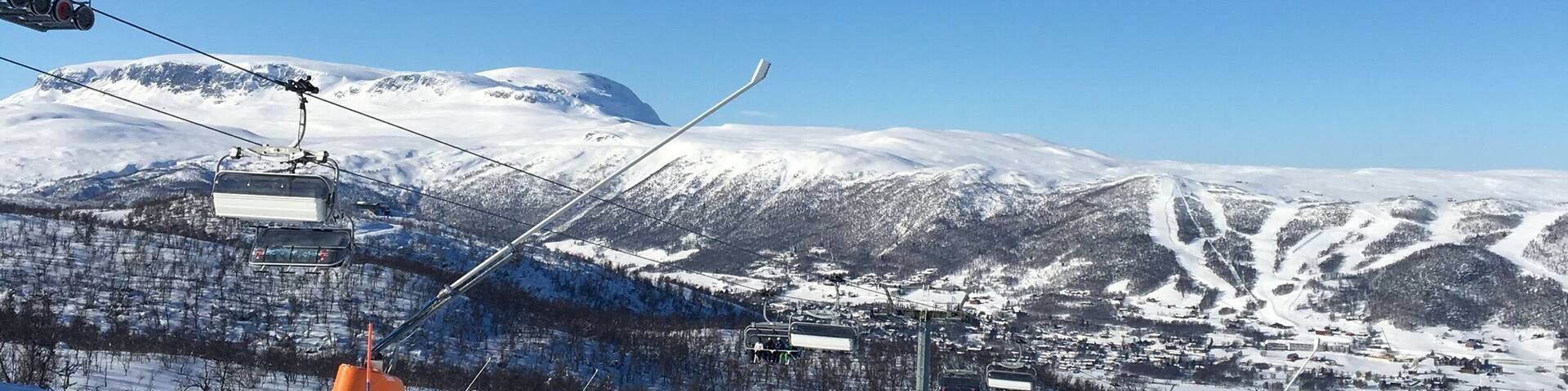 A snowy mountain landscape with ski lifts and tracks.
