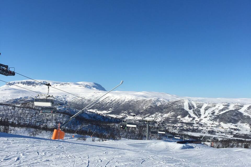 A snowy mountain landscape with ski lifts and tracks.