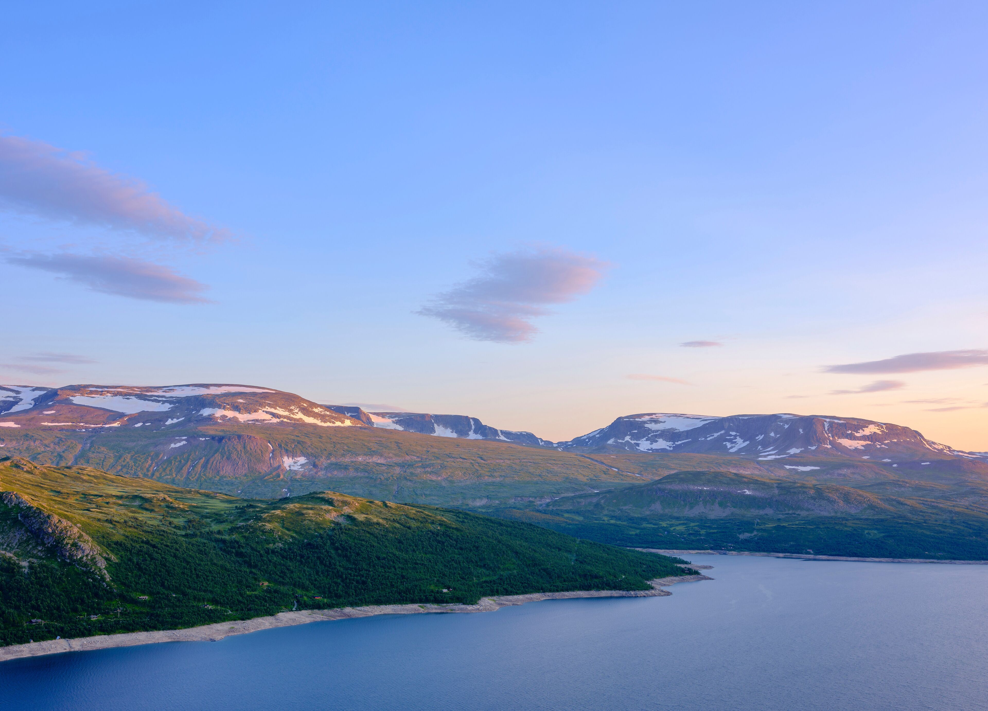 Paisagem montanhosa com um lago e picos nevados.