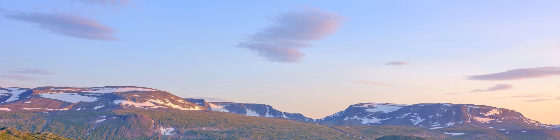 Paisagem montanhosa com um lago e picos nevados.