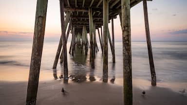 A wooden pier extending into calm waters at sunset.